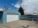 Exterior of detached blue garage with white door; gravel driveway, fence, and some yard growth at 1965 Havana St, Aurora, CO 80010