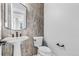 Stylish half-bathroom with gray tile accent wall, modern sink, and toilet at 6633 Bridlespur St, Castle Pines, CO 80108
