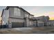 A two-story home showcases gray siding, stone accents and a two car garage with a concrete driveway during sunset at 6633 Bridlespur St, Castle Pines, CO 80108