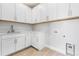 Bright laundry room with white cabinets, sink, and herringbone flooring at 6633 Bridlespur St, Castle Pines, CO 80108