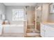 Elegant bathroom with a soaking tub, glass shower, and neutral tile, offering a spa-like experience at 8367 Devinney St, Arvada, CO 80005