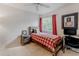 Cozy bedroom with a rustic wooden bed frame, red plaid comforter, and matching curtains, offering a warm ambiance at 8367 Devinney St, Arvada, CO 80005