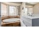 Bright bathroom with a large soaking tub in a tiled alcove with a bay window at 2257 Deerpath Rd, Franktown, CO 80116