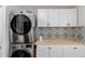 Modern laundry room with stackable washer/dryer and decorative backsplash at 2257 Deerpath Rd, Franktown, CO 80116