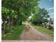 Long gravel driveway lined with mature trees and lush landscaping leading to a home at 5870 Nelson Ct, Arvada, CO 80004