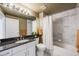 Bathroom with granite counters, white cabinets, and a shower/tub combo with marble-look tile at 111 S Monroe St # B203, Denver, CO 80209