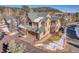 Aerial view of a tan two-story home with a two-car garage and a green roof nestled in a wooded neighborhood at 1294 Red Lodge Dr, Evergreen, CO 80439