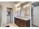 Bathroom featuring dual sinks with granite countertops, wood cabinets, and tiled floor at 8300 Fairmount Dr # Aa102, Denver, CO 80247