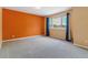 Large bedroom with bright orange accent wall, tan walls, and a window at 1160 S Clinton St # 40, Denver, CO 80247