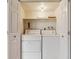 A laundry room with white washer and dryer, storage shelving, and light at 1160 S Clinton St # 40, Denver, CO 80247