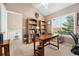 Bright home office with a desk, built-in bookcases, and large window view at 6819 S Webster St # E, Littleton, CO 80128