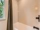 Bathroom with beige tiled shower/tub combo with dark fixtures and a large window at 5206 S Meadow Lark Dr, Castle Rock, CO 80109