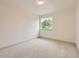 Empty bedroom featuring neutral carpeting, base trim, and a window with a tree view at 5206 S Meadow Lark Dr, Castle Rock, CO 80109