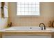 Close-up of a bathtub with tiled walls and a window; includes an elegant black faucet at 11830 Snowshoe Dr, Parker, CO 80138