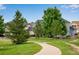 Neighborhood view of well-maintained homes along a green walkway with mature trees at 11830 Snowshoe Dr, Parker, CO 80138