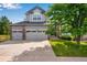 Charming two-story home with a three-car garage, manicured lawn, and mature landscaping at 11830 Snowshoe Dr, Parker, CO 80138