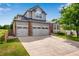 Charming two-story home with a three-car garage, manicured lawn, and mature landscaping at 11830 Snowshoe Dr, Parker, CO 80138