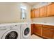 Bright laundry room with Whirlpool washer and dryer, wooden cabinets and tiled floor at 11830 Snowshoe Dr, Parker, CO 80138