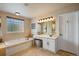 Bright main bathroom with a soaking tub, tiled walls, vanity, and white cabinetry at 11830 Snowshoe Dr, Parker, CO 80138
