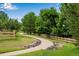 Community walking path winding through mature trees, green grass, and wooden fences on a sunny day at 11830 Snowshoe Dr, Parker, CO 80138