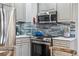 Close-up of the kitchen with stainless steel appliances, a gas range, and stylish blue tile backsplash at 1965 Jasmine St, Denver, CO 80220