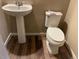 Powder room featuring a pedestal sink, toilet, and wood-look floors at 4280 E Warren Ave # 2, Denver, CO 80222