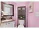 Small bathroom with colorful pink walls, granite counters, and white cabinets at 5432 S Cathay Way, Centennial, CO 80015