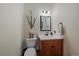 Powder room with a wood vanity, white sink, and a mirror lit by a modern sconce at 17313 W 43Rd Dr, Golden, CO 80403