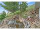 Backyard pond featuring rock landscaping, a small waterfall, and lush landscaping on a sunny day at 17313 W 43Rd Dr, Golden, CO 80403
