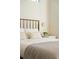 A close up shot of a bright bedroom with brass bed frame, stylish clock and table lamp on a white night stand at 1815 N Williams St, Denver, CO 80218