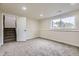 Open basement with a large window, door to stairs, and carpeted floor at 7325 Taft Ct, Arvada, CO 80005