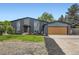 Split level home with black brick and siding, a well manicured lawn, and a two car garage at 7325 Taft Ct, Arvada, CO 80005