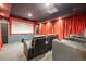 Enjoy movie night in this cozy home theater with comfortable seating, projection screen, and red curtains at 13324 W 86Th Dr, Arvada, CO 80005