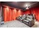 This home theater boasts plush leather seating, a large projection screen, and dramatic red curtains at 13324 W 86Th Dr, Arvada, CO 80005