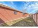 A grassy backyard with a brick house and a wooden fence under a sunny blue sky at 4501 Bryant St, Denver, CO 80211