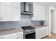 Close up of gourmet kitchen showcasing gray fish-scale backsplash, stainless steel stove and white cabinetry at 11103 Cloud Shadow St, Littleton, CO 80125
