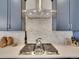 Close up on the cooktop area with stainless steel vent hood and mosaic tile backsplash at 8894 River Peak Cir, Littleton, CO 80125