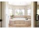 Spa-like bathroom showcasing an oval soaking tub and picture windows with privacy shades at 5184 Pinyon Jay Rd, Parker, CO 80134