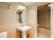 Bathroom with pedestal sink, oval mirror, and glass shower doors at 5184 Pinyon Jay Rd, Parker, CO 80134