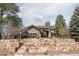 Majestic stone home with mature trees, stone retaining wall, and landscaped front yard at 5184 Pinyon Jay Rd, Parker, CO 80134