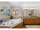 A luxurious bathroom boasts a soaking tub next to a window and separate vanities with granite countertops at 7737 Taylor Cir, Larkspur, CO 80118