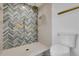 Bright bathroom featuring a stylish shower with gold fixtures and herringbone tile design at 2961 S Rosemary St, Denver, CO 80231
