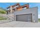 Modern home with a large garage door, stone accents, and hillside landscape at 202 October Pl, Castle Rock, CO 80104