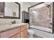 Bathroom with granite countertop vanity, a glass-enclosed tub, and neutral earth tone tile at 177 W 8Th Ave, Byers, CO 80103