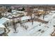 Aerial view of a home in a snowy neighborhood with mature trees and a red front door at 7250 W Vassar Ave, Lakewood, CO 80227