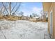 Large backyard featuring a stone retaining wall, a deck and a partially snow covered lawn at 7250 W Vassar Ave, Lakewood, CO 80227