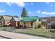 Charming home with a green metal roof, covered porch, fenced yard, and well-manicured lawn at 829 Colorado Blvd, Idaho Springs, CO 80452
