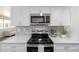 Modern kitchen featuring stainless steel appliances, white cabinets, and light gray backsplash at 3611 W 79Th Ave # B4, Westminster, CO 80030