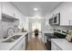 Galley kitchen with white cabinets and stainless steel appliances, leading to a dining area at 3611 W 79Th Ave # B4, Westminster, CO 80030