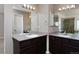 Bathroom featuring dual sinks, large mirrors, and dark cabinets at 9436 Cody Dr, Broomfield, CO 80021